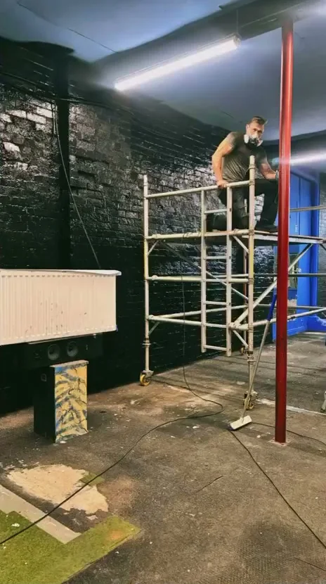 Painting the brick walls black from a scaffold tower